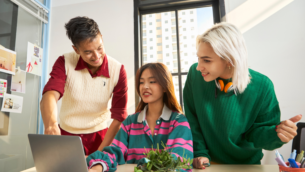 Three members of a charity retail team gathered around a laptop.