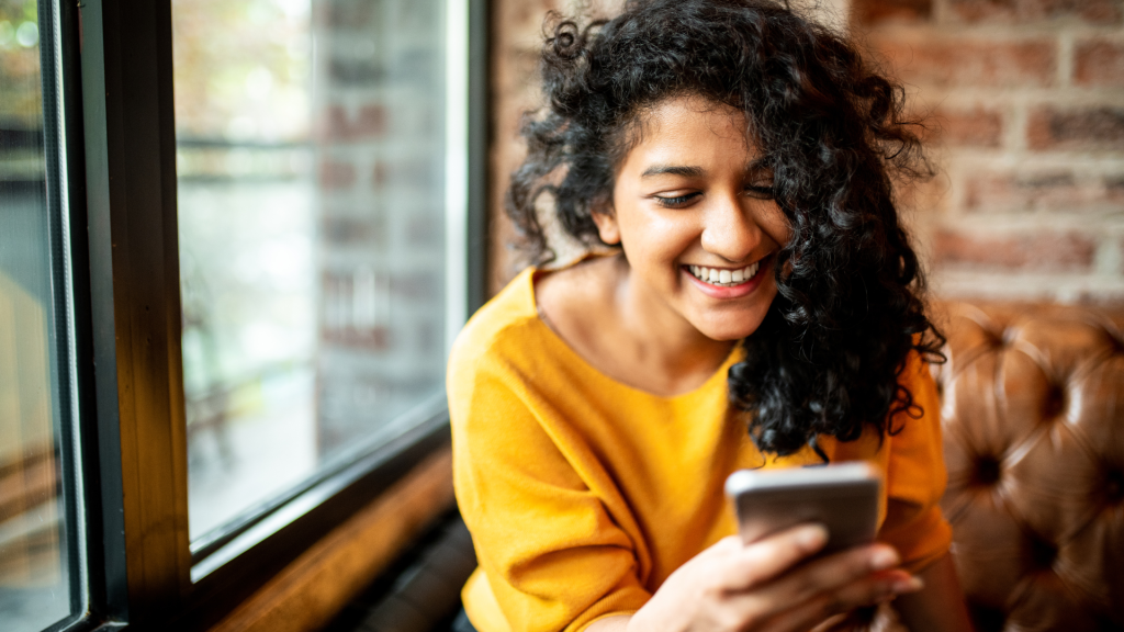 Woman smiling and looking at phone.