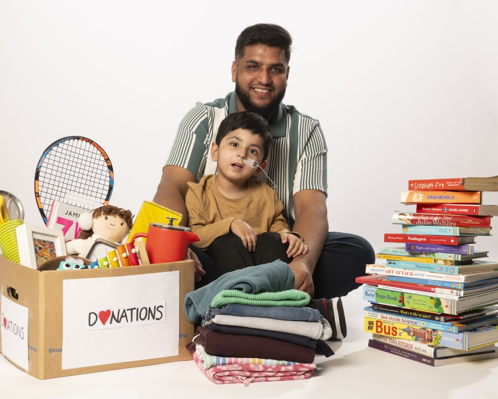 Man and child surrounded by charity donations.