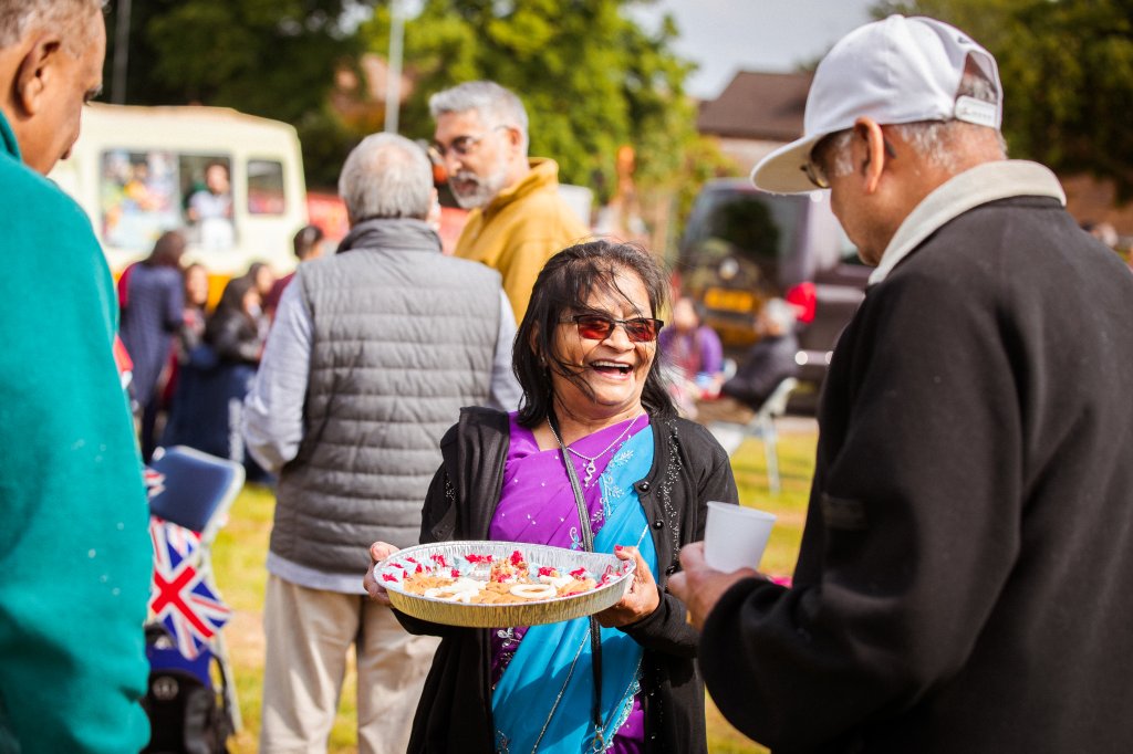 People smiling and sharing food outside.