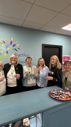 Charity retail team holding award posing behind till
