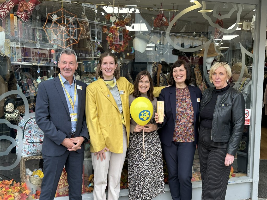 Charity shop team celebrate award win outside shop.